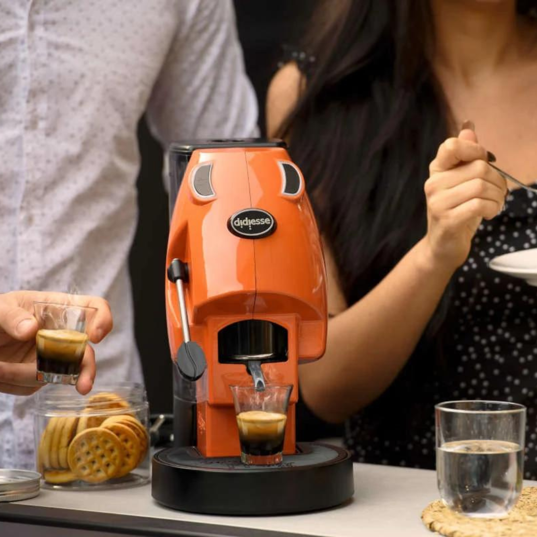 a woman is pouring a drink into a didiesse baby frog coffee machine