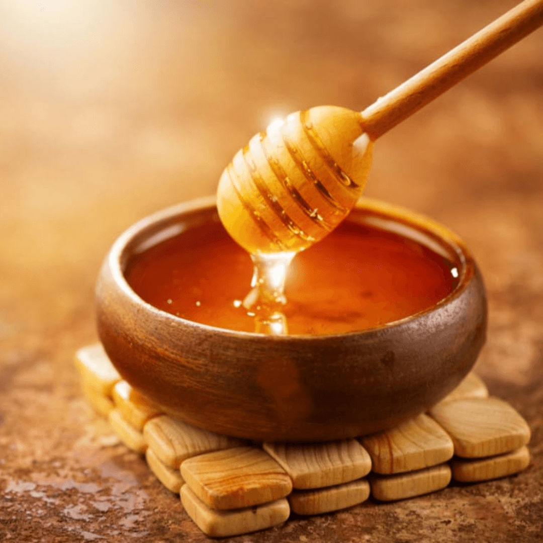 a bowl of honey with wooden dispenser